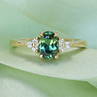 Handmade cluster engagement ring by Lilia Nash, set with an ethical central sapphire surrounded by diamonds in recycled gold.