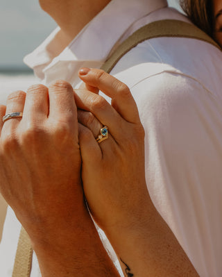 A couple wearing Lilia Nash molten platinum wedding band and blue sapphire trilogy engagement ring and wishbone wedding ring