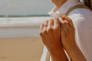 A couple wearing Lilia Nash molten platinum wedding band and blue sapphire trilogy engagement ring and wishbone wedding ring