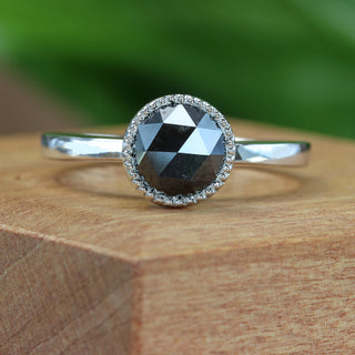 Handmade platinum black diamond engagement ring with rose cut diamond on wooden block.