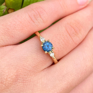 18ct gold blue sapphire and diamond trilogy engagement ring shown worn on hand.