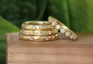 A stack of handmade 18ct gold eternity rings, set with fair trade diamonds and hand engraved patterns.