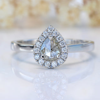 Handmade rose cut diamond halo engagement ring on white floral background.