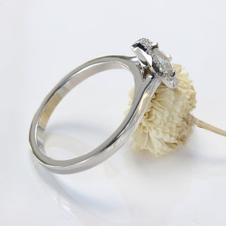 Side view of platinum pear diamond halo ring on display stand.
