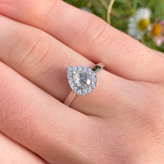 Platinum pear diamond halo engagement ring shown worn on hand.