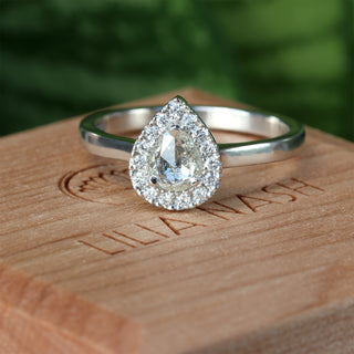 Platinum pear diamond halo engagement ring photographed outdoors.