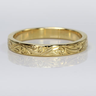 A 3mm wide 18ct gold wedding band with a flat profile, featuring a floral scroll pattern engraved around the outer band