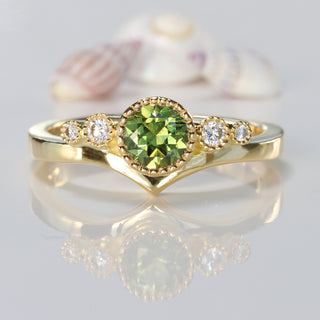 18ct gold green sapphire and diamond wishbone engagement ring on reflective surface