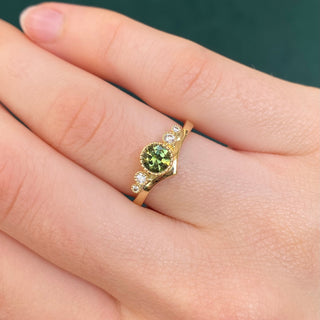 18ct gold green sapphire wishbone engagement ring shown worn on hand.