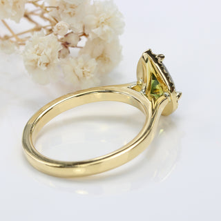 green sapphire and diamond halo ring rear profile of the setting, with white floral background.