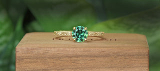Green sapphire solitaire engagement ring with hand engraved orange blossom pattern