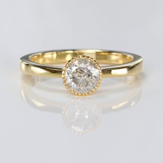 Handmade 18ct gold salt and pepper diamond solitaire ring with milgrain bezel on reflective surface.