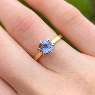 Lavender blue sapphire solitaire engagement ring in 18ct gold shown worn on hand.