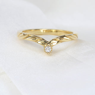 Hand-engraved leaf wishbone ring with Canadian diamond accent displayed on soft linen