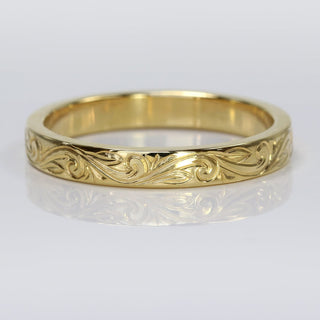 18ct gold floral scroll engraved ring on a white surface