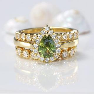 Pear cut green sapphire and diamond halo ring with milgrain diamond wedding and eternity bands