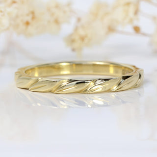 18ct gold leaves wedding band on a white surface with flowers