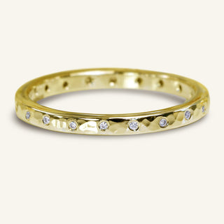 Handmade 18ct gold slim profile wedding ring set with twenty scattered natural diamonds. The band has a hammered finish applied.