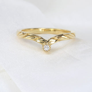 Hand-engraved leaf wishbone ring with Canadian diamond accent displayed on soft linen