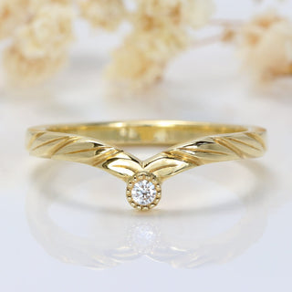 Diamond 18ct gold wishbone wedding ring with hand-carved leaves on white background with flowers