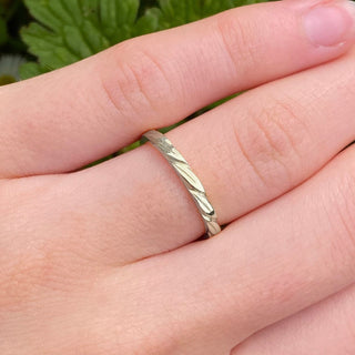 18ct white gold wedding band with hand-carved leaves around the band shown on a hand
