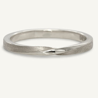 Sustainable 950 platinum slim wedding band with a twist at the front of the band. The handmade band has our signature spun silk finish applied.