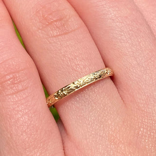 9ct gold court wedding ring with hand engraved orange blossom pattern, being worn on the hand