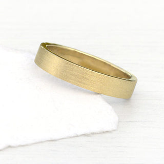 9ct gold 4mm wide flat profile wedding band with spun silk finish on a white surface 