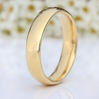 9ct gold 5mm wide wedding band on a white surface with flowers