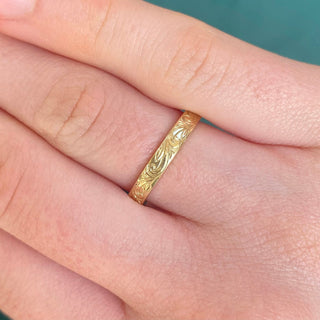 9ct gold Floral scroll engraved 3mm flat profile wedding band, being worn on the finger