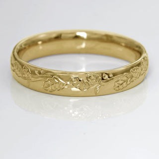 9ct gold 4mm court wedding band with hand engraved oak leaves, on a white surface