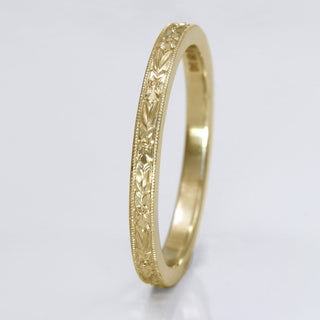 9ct gold slim wedding band with hand engraved orange blossom pattern, on a white surface