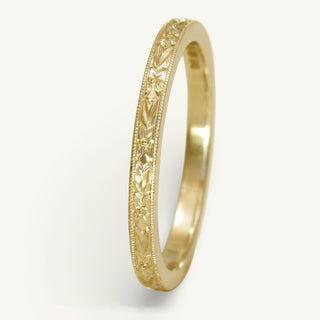 9ct gold slim wedding band with hand engraved orange blossom pattern, on a white surface