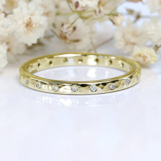 9ct gold slim hammered wedding band set with 20 diamonds on a white surface with flowers