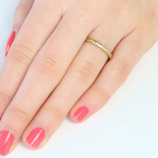 9ct gold slim hammered wedding ring set with 7 diamonds at the front worn on the hand