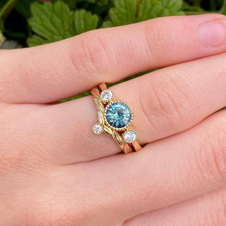 Solitaire diamond 9ct gold wishbone wedding ring with hand engraved leaves and sapphire and diamond trilogy ring worn on the hand