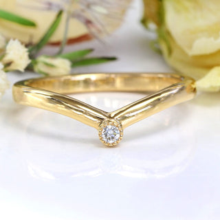 9ct gold diamond solitaire wishbone wedding ring on a white surface with flowers