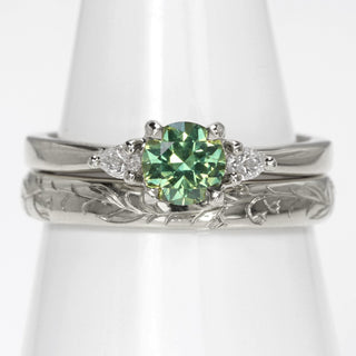 Platinum green sapphire and diamond trilogy engagement ring with bluebells hand engraved wedding band