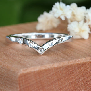 Custom made platinum diamond wishbone wedding ring on a wooden box with white flowers