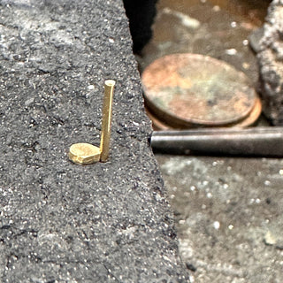 Adding a claw to the setting of a handmade gold trilogy engagement ring  on a jeweller's soldering block