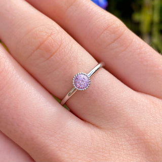 Platinum pink sapphire solitaire engagement ring shown worn on hand.