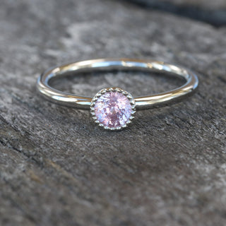 Close up of platinum pink sapphire solitaire ring on grey wood
