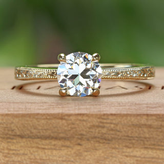 18ct gold solitaire engagement ring set with a 1 carat old European cut lab diamond. Finished with hand engraved orange blossom detail on the band