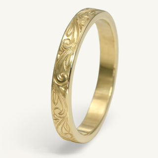 18ct gold wedding band with hand engraved floral scroll pattern on a white surface