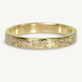 A 3mm wide 18ct gold wedding band with a flat profile, featuring a floral scroll pattern engraved around the outer band