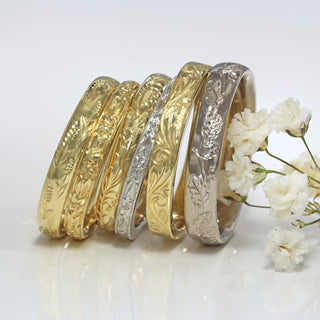 A selection of 18ct gold and platinum wedding bands with hand engraved floral patterns
