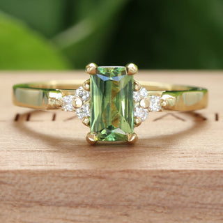 18ct gold fair trade emerald cut parti sapphire ring with a cluster of natural diamonds, on a wooden ring box