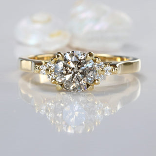 Salt and pepper diamond cluster 18ct gold engagement ring on reflective surface.