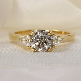 18ct gold engagement ring with salt and pepper diamond and Canadian diamond accents photographed on pale fabric.