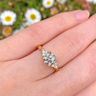 One of a kind salt and pepper diamond cluster ring, handmade from sustainable 18ct gold. Being worn on the hand with daisy background